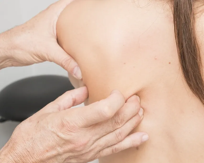 Die Hände einer Physiotherapeutin lösen die Muskulatur am Schulterblatt einer Patientin